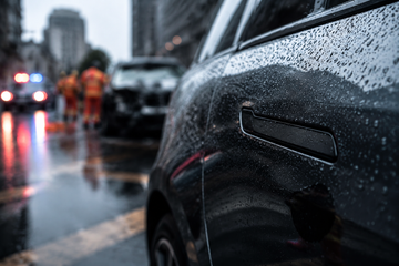 Retracted Tesla door handle on Model 3 in rainy Chinese street with emergency responders in background