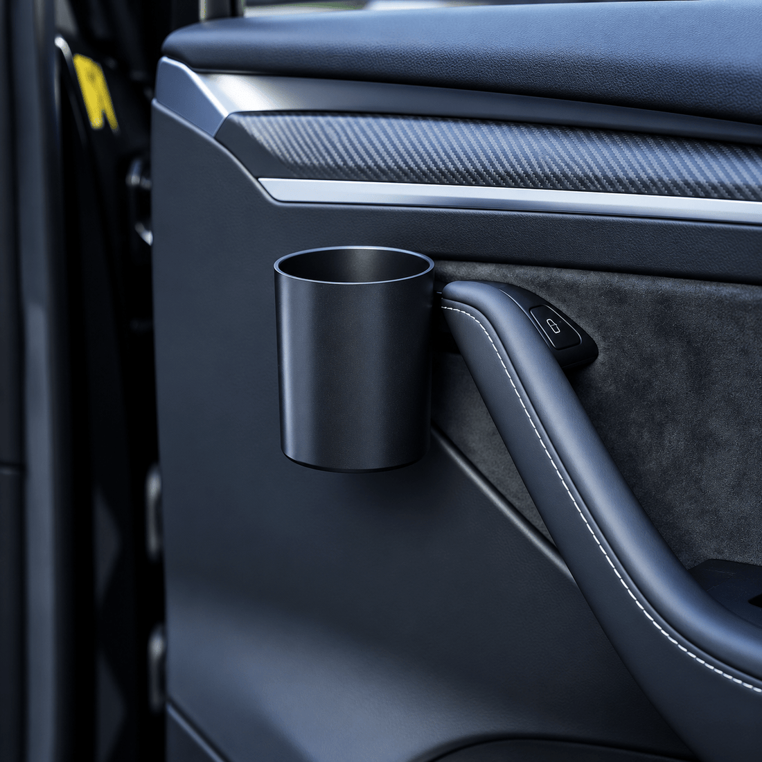 Empty black cylindrical cup holder mounted beside the interior door pull on a dark Tesla door panel.