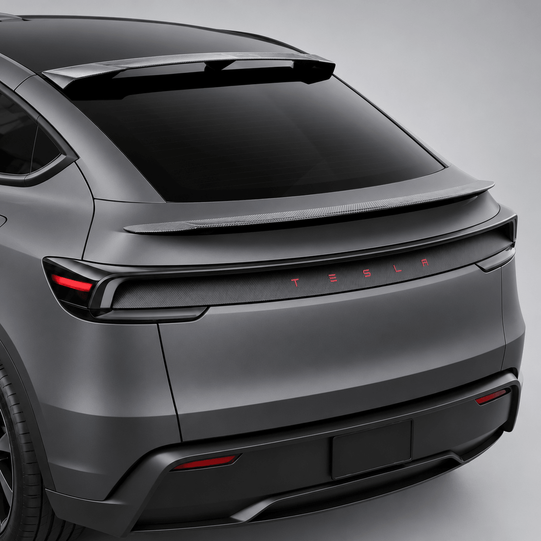 Rear three-quarter view of a gray Model Y Juniper with a roof spoiler, rear spoiler and carbon-weave tailgate trim.