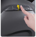 Finger lifting a TESERY folding seat-back hook, with an upward arrow showing how it opens.