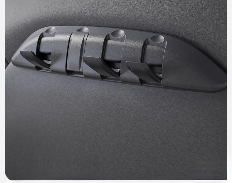 Angled close-up of a TESERY seat-back organizer installed in a Tesla, with several hooks open.